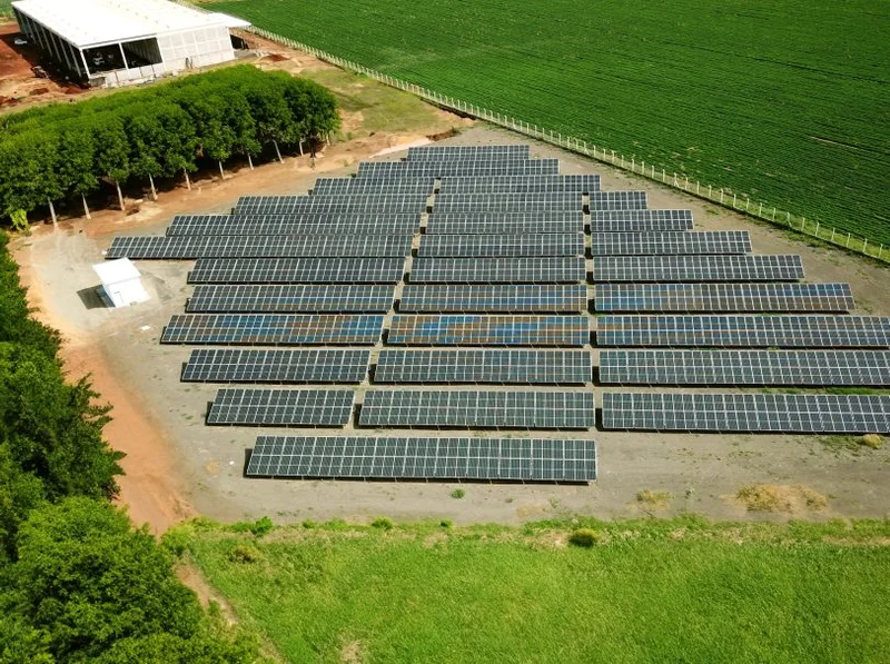 Usina solar montada no solo, na beira de uma lavoura, vista de cima
